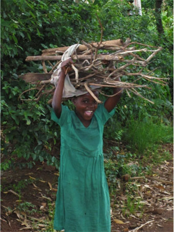 An African child carrying some sticks.