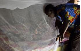 A father putting his daughter under a bednet in Burkina Faso - Photo credit: Jed Stone