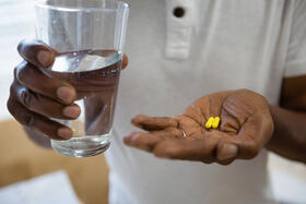 person holding medicines and drinking water