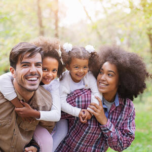 Portrait Of Parents Giving Children Piggybacks stock photo