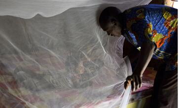 Father putting his daughter under a bednet in Burkina Faso
