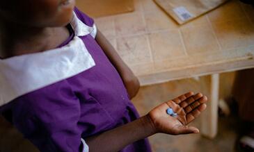 Image of child's hand holding a medical pill
