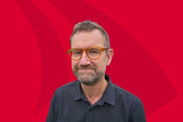 Portrait photo of Professor Julian Eaton on a red background