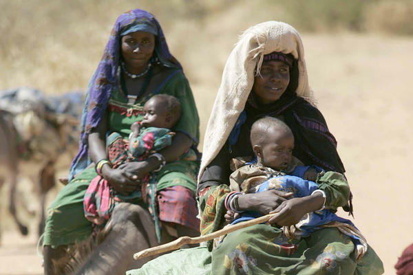 Women with their children on donkeys make their way along a road side in Goz Beida, Chad, Africa.