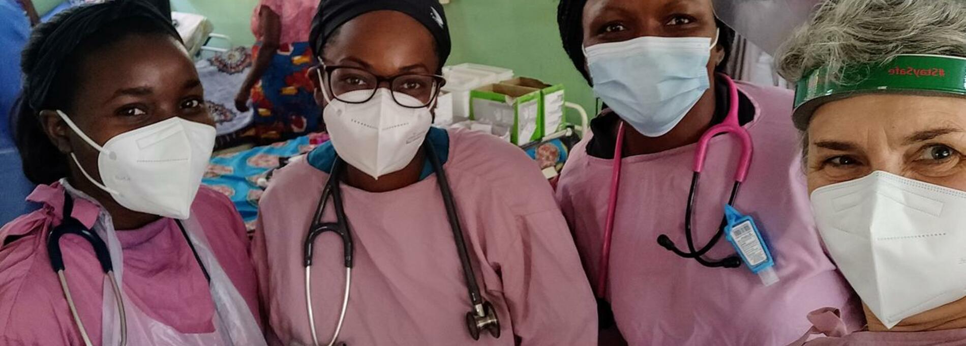 4 nurses in pink ppe standing in a hospital ward in Malawi