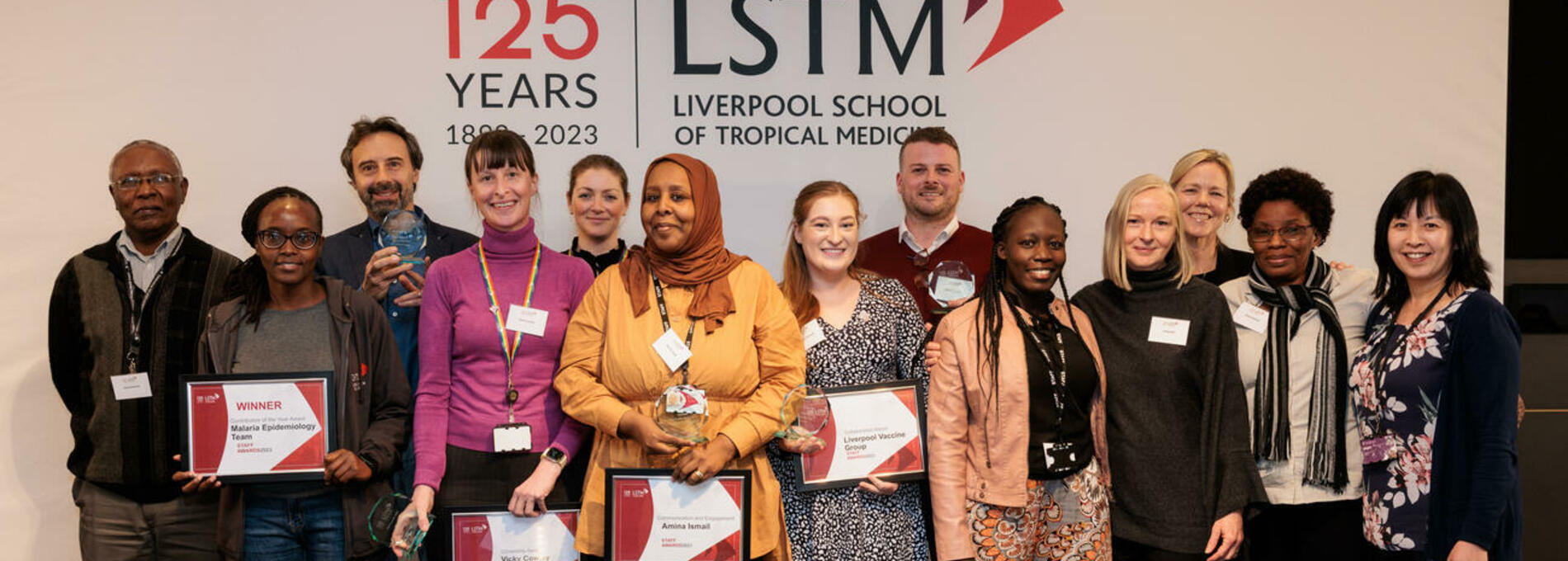 Image of award winners standing in front of the LSTM logo