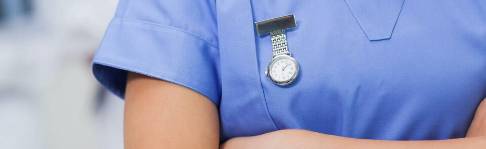 Nurse with arms crossed and hanging watch in hospital