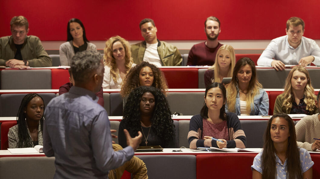 Back view of man presenting to students at a lecture 