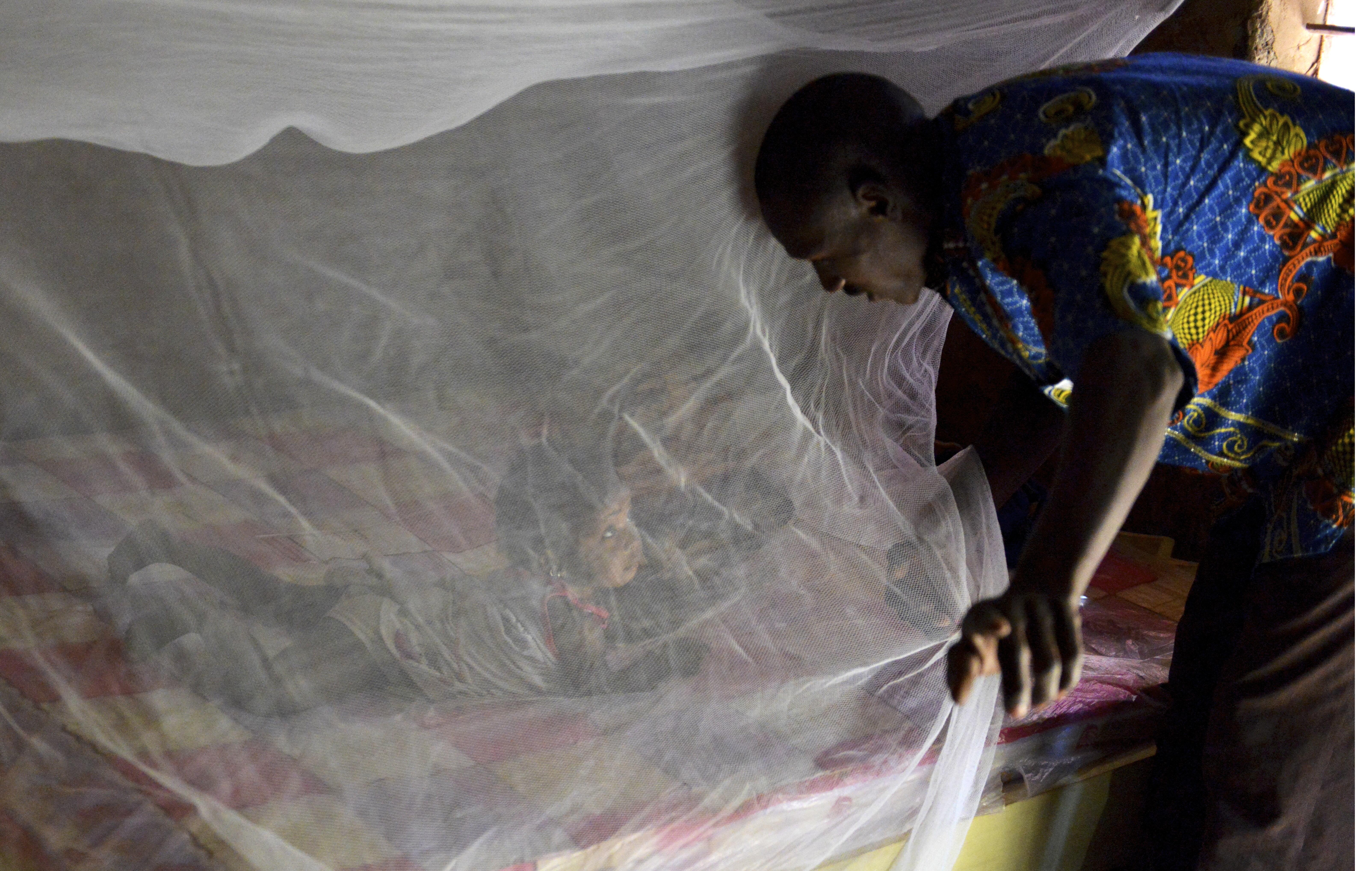 Father putting his daughter under a bednet in Burkina Faso