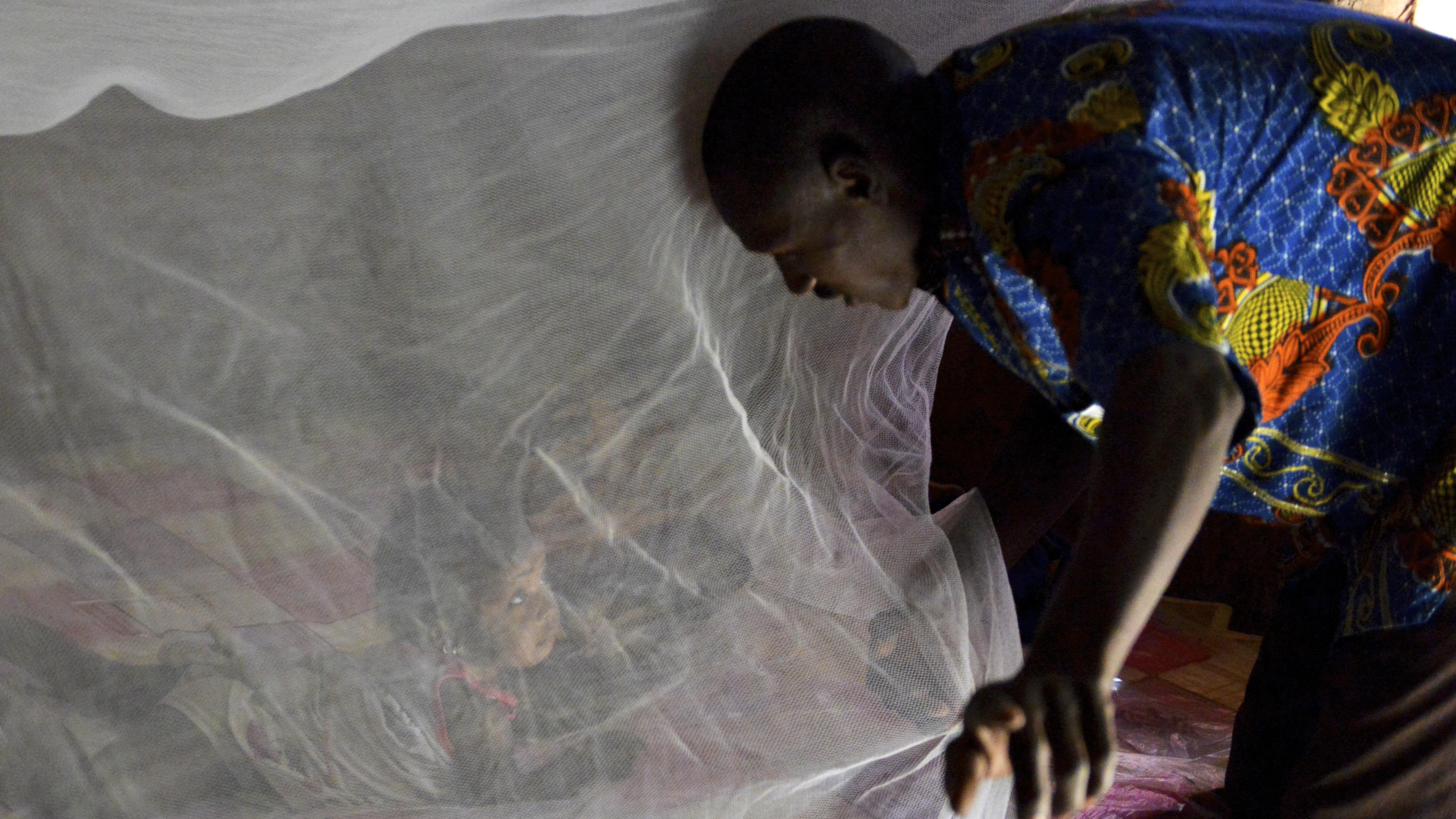 A father putting his daughter under a bednet in Burkina Faso - Photo credit: Jed Stone