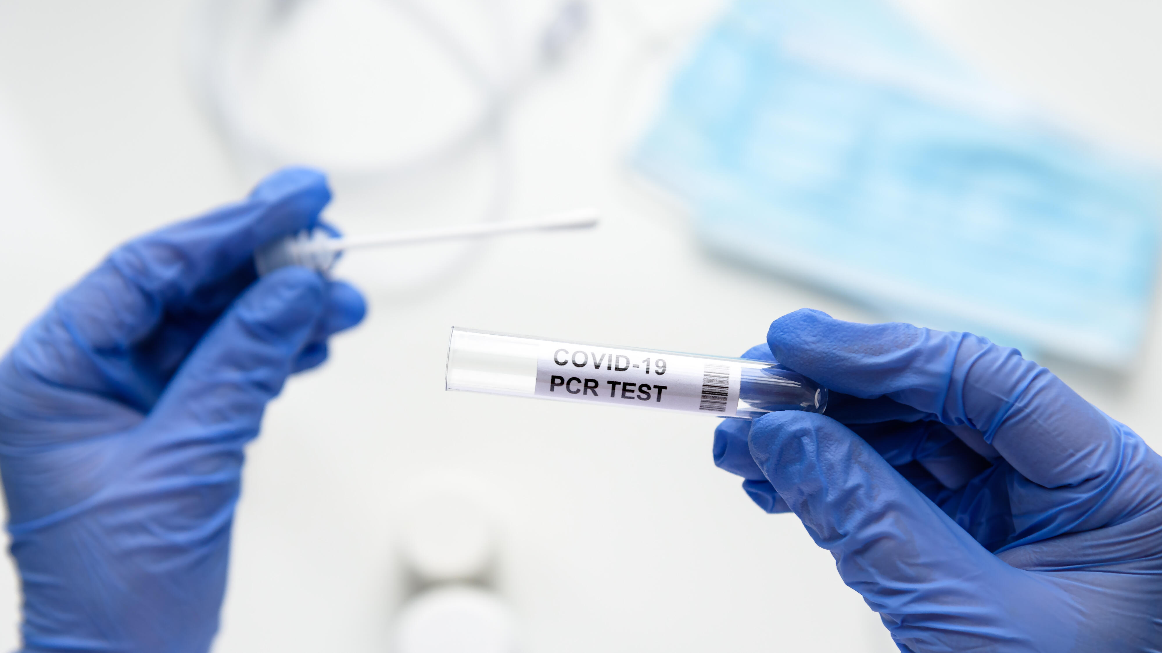 Nurse holds tube of COVID-19 swab collection kit in laboratory