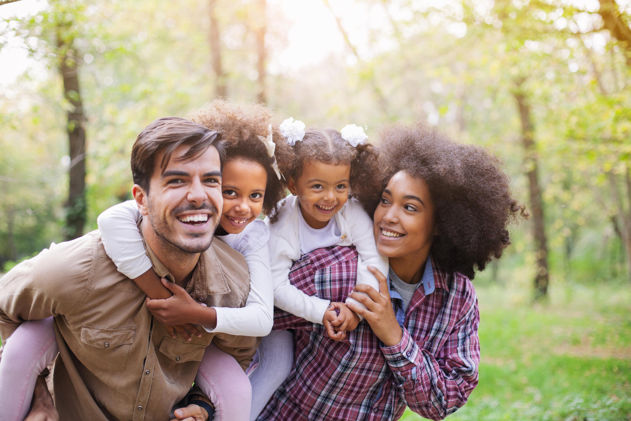 Portrait Of Parents Giving Children Piggybacks stock photo