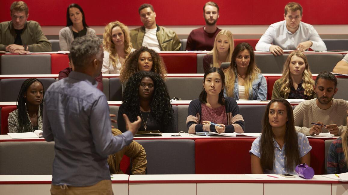 Back view of man presenting to students at a lecture 