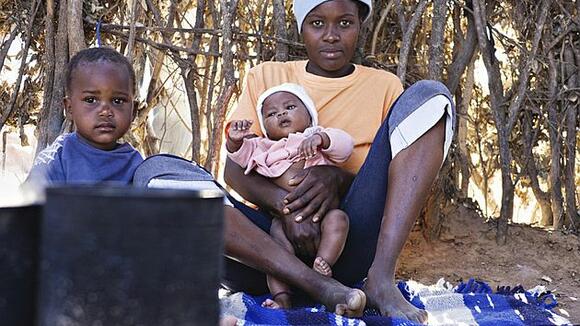 Mother, baby and child resting on a blanket in the shade