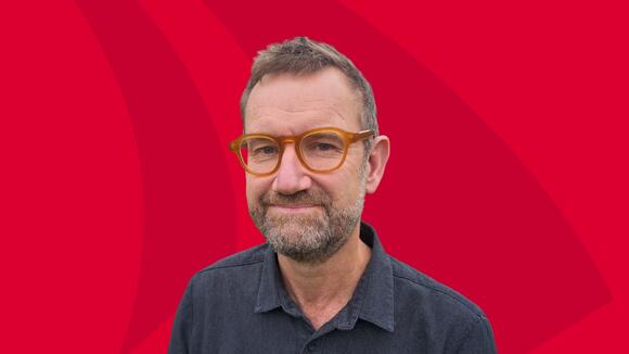 Portrait photo of Julian Eaton on a red background
