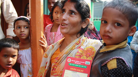 A woman with her 'red health card', which allows her to access government health services in the Korail slum, Dhaka, Bangladesh. Photo: Lucy Milmo/DFID