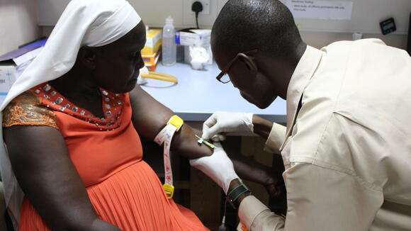 Wycliffe Onyango, clinical officer, draws blood for mosquito feeding from one of the study patients [patient gave written consent to publish photo]