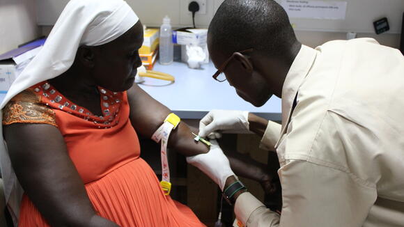 Wycliffe Onyango, clinical officer, draws blood for mosquito feeding from one of the study patients [patient gave written consent to publish photo]