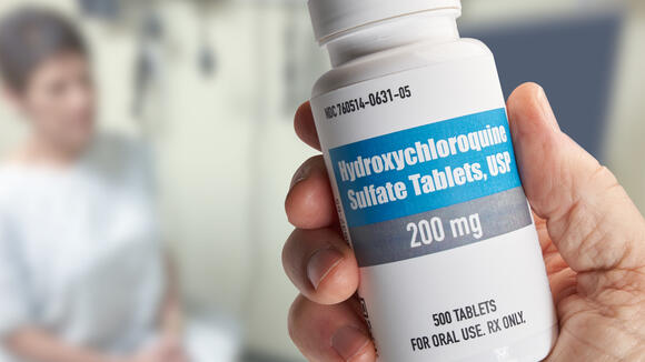 Hydroxychloroquine bottle held in hand in doctors office with patient